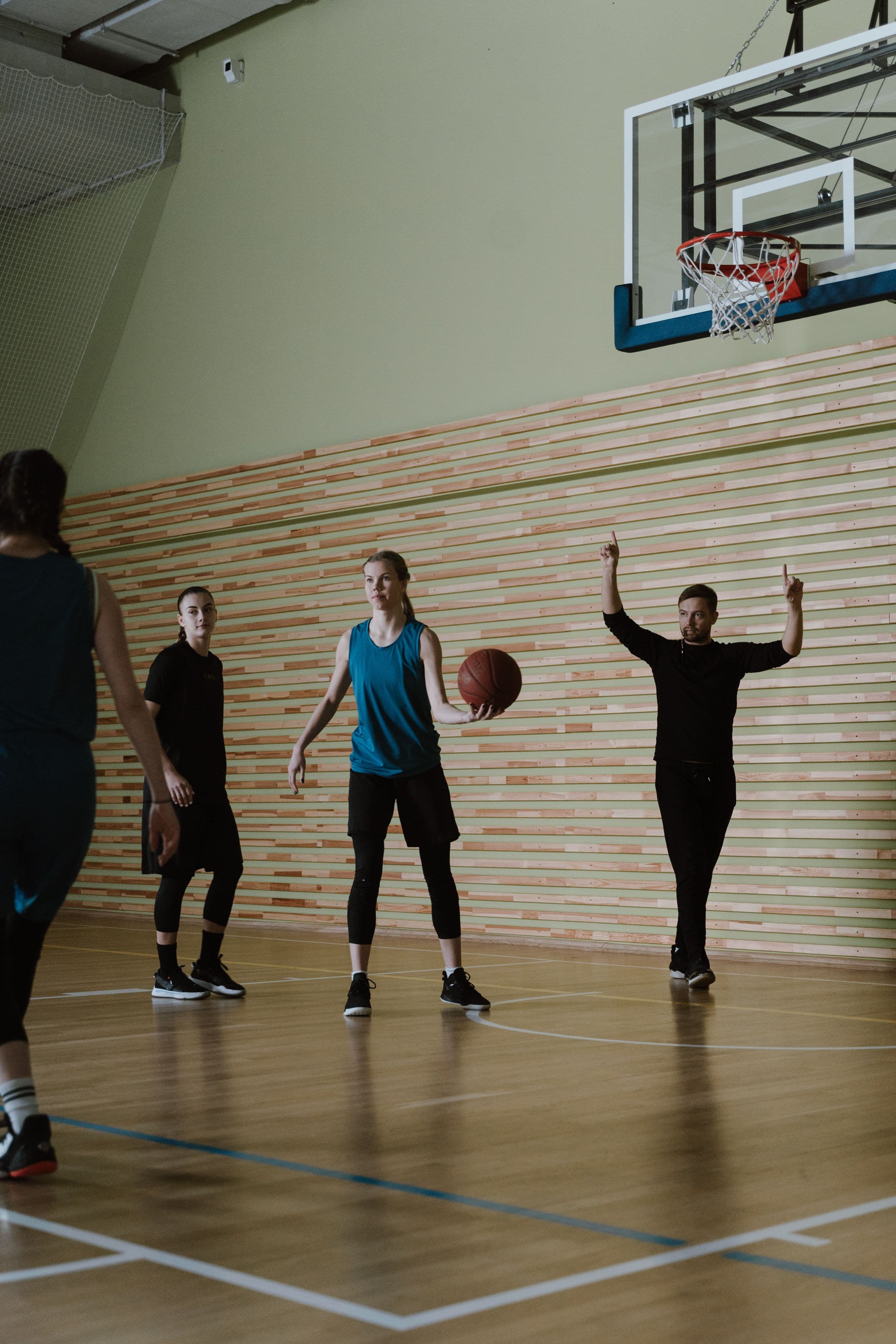 Séance d'entraînement de basket en salle avec coach et joueuses.